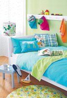 Kinderbett in Weiß, Bettwäsche blau und grün, Wand hellgrün