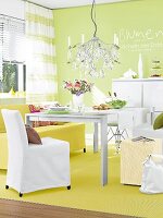 Dining area with chandelier, table, chair and yellow carpet against green wall