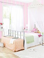 View of bedroom in white and pink with four poster bed