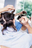 Frau steckt Haarpartie am Hinterkpf fest, Haaransätze selbst färben