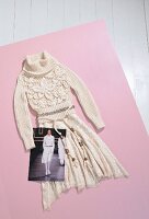 Knitted sweater and skirt with belt on pink background