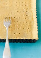 Close-up of dough in corrugated baking pan being poked with fork