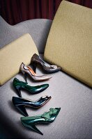 Div. Schuhe in Braun, Grün, Schwarz liegen in Reihe auf Sofa in Grau