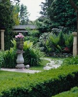 Stoned path through garden with Buddha head shaped flower pot with fern