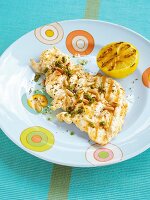 Grilled chicken breast with capers, pine nuts and grilled lemon served on plate