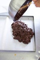 Close-up of chef pouring chocolate mixture on baking sheet