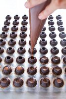 Canache wird durch Spritzbeutel in Hohlkugeln aus Schokolade gedrückt