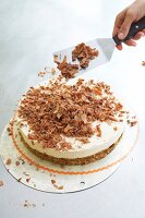 Close-up of chef spreading grated chocolate on walnut cake