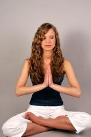 Young woman with long wavy hair performing yoga with eyes closed