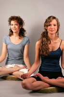 Two women sitting and performing yoga