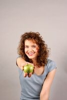 Janine hält Apfel in der Hand in die Kamera und lacht