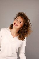 Portrait of beautiful woman with curly hair wearing white sweater, smiling widely