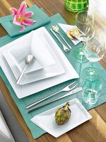 White square plates on turquoise table mat with pink flower on side