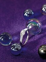 Platinum ring with diamond on purple background with balls