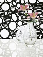 Glasvasen mit  Querstreifen vor Stoff mit Muster in Schwarz-Weiß