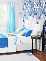White double bed with patterned wallpaper and blue curtains in bedroom