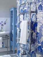 Bathroom with sink, blue cabinet and towel hanger against Asian style silver wallpaper