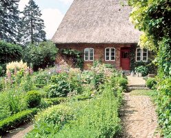Farmhouse with thatched roof in lush garden