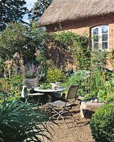 2 Stühle am Tisch im grünen Garten, Bauernhaus im Hintergrund