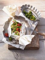 Noodles with cabbage, tomatoes and olives in parchment paper