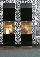 Illuminated display case with black and white patterned wallpaper and chair