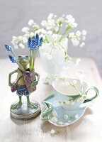 Table decorated with frog figurine, flowers, tea cup and saucer
