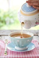 Close-up of herbal tea being poured in teacup