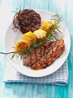 Marinated steak with roasted corn and sprig of rosemary on plate