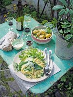 Gurken-Nudel-Salat, Spinat-Kartoffel-Salat und Rotwein auf Gartentisch
