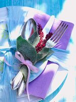Leaves and knotweed flowers tied with cutlery and napkin on plate