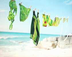 Various green patterned bikini hanging on clothes line