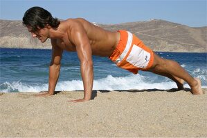 A man doing pushups on the beach