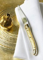 Messer mit goldenen Kunststoffgriff, Serviette, Teller, Nr 4