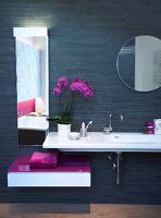 Weißes, langes Waschbecken an schwar zer Wand, 2 Spiegel, pinke Ablage