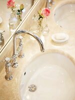 Close-up of two sinks in marble with silver faucets, rose and soap
