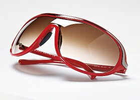 Rote Sonnenbrille mit grauem Streifen, braune Gläser