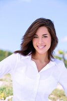 Portrait of beautiful brunette woman wearing white blouse, smiling