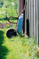 Schubkarre lehnt aufgestellt an einem Gartenzaun