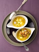 Two bowls of turnip soup with chanterelles on one bowl on serving dish