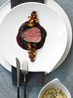 Fillet of sauerbraten with dried cherries and rosemary spaetzle on white plate