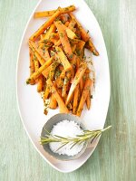 Carrots in balsamic sauce with rosemary on plate and sea salt in small bowl