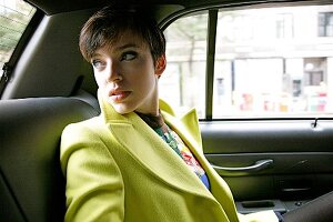 Anxious woman with short hair sitting in car looking back over shoulder