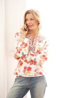 Beautiful blonde woman standing while talking on phone looking away, smiling