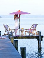 Woman opening parasol with folding deck chairs on dock