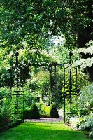 A rose arch and obelisks in a resplendent garden