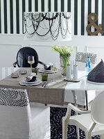 Dining table in black and white with chairs, lamp and striped wallpaper