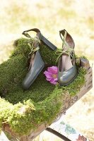 Pair of green faux leather pumps with flower on wooden box