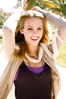 Portrait of beautiful blonde woman wearing scarf over top, smiling widely in sunlight