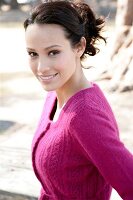 Portrait of beautiful brunette woman wearing pink cardigan, smiling