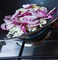 Red onions, ginger and garlic being fried in wok